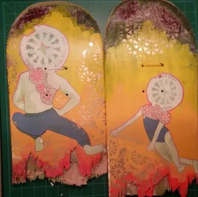A broken skateboard featuring one of Kelly’s 100 characters